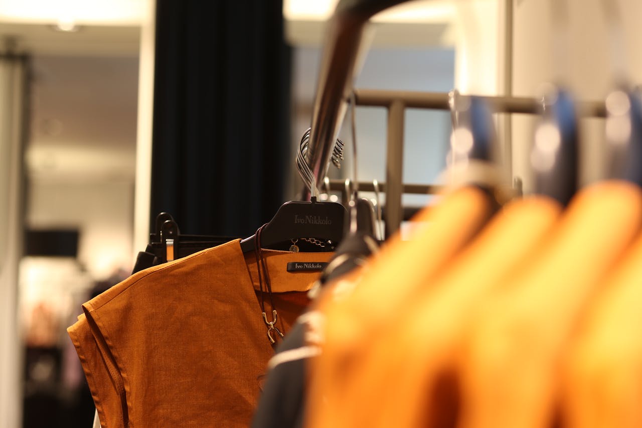 Close-up of clothing hanging in a well-lit fashion boutique, showcasing trendy styles.